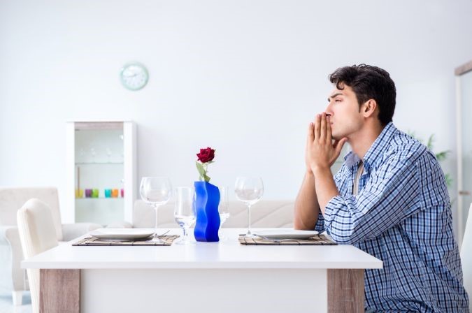 man sitting alone at table with single rose